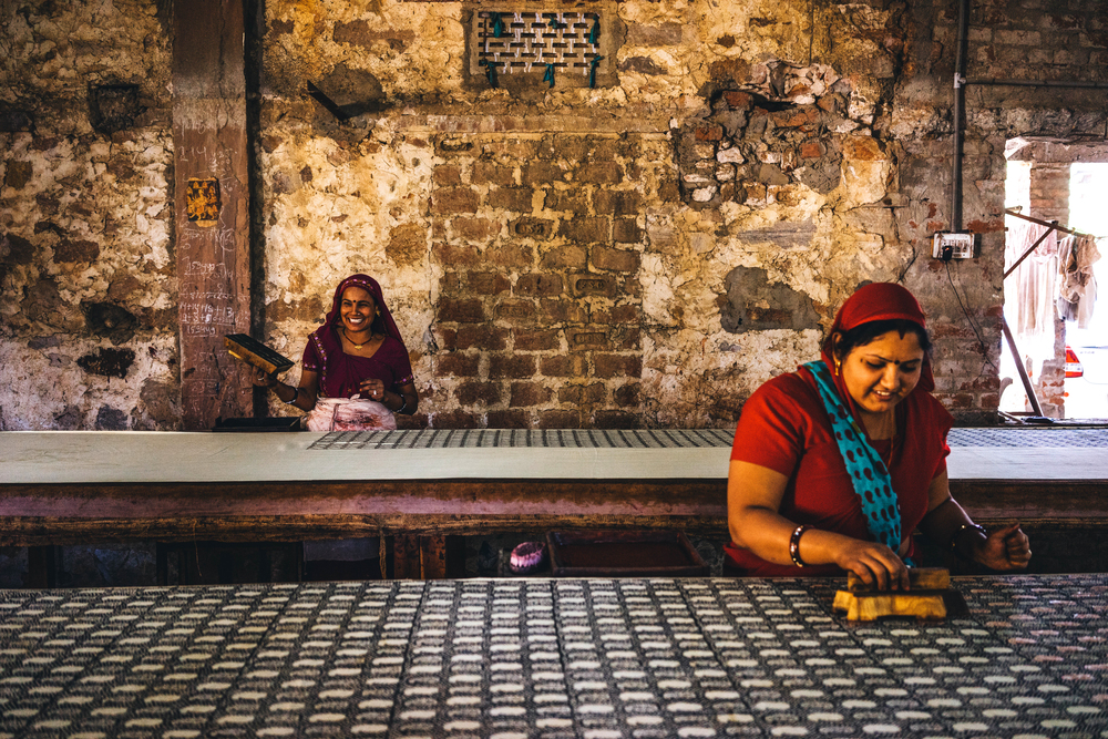 Block printing artisans share a light moment while working at a block printing unit in Bagru, outskirts of Jaipur in Rajasthan, India; Photo courtesy of Piece & Co.